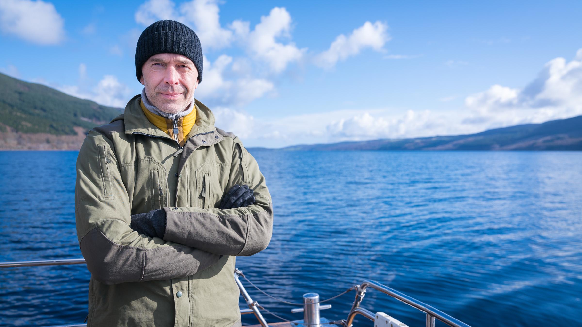 "Terra X: Rätselhafte Phänomene -  Sternengold und der Hauch des Todes": Dirk Steffens steht auf einem Boot im See und schaut in die Kamera.