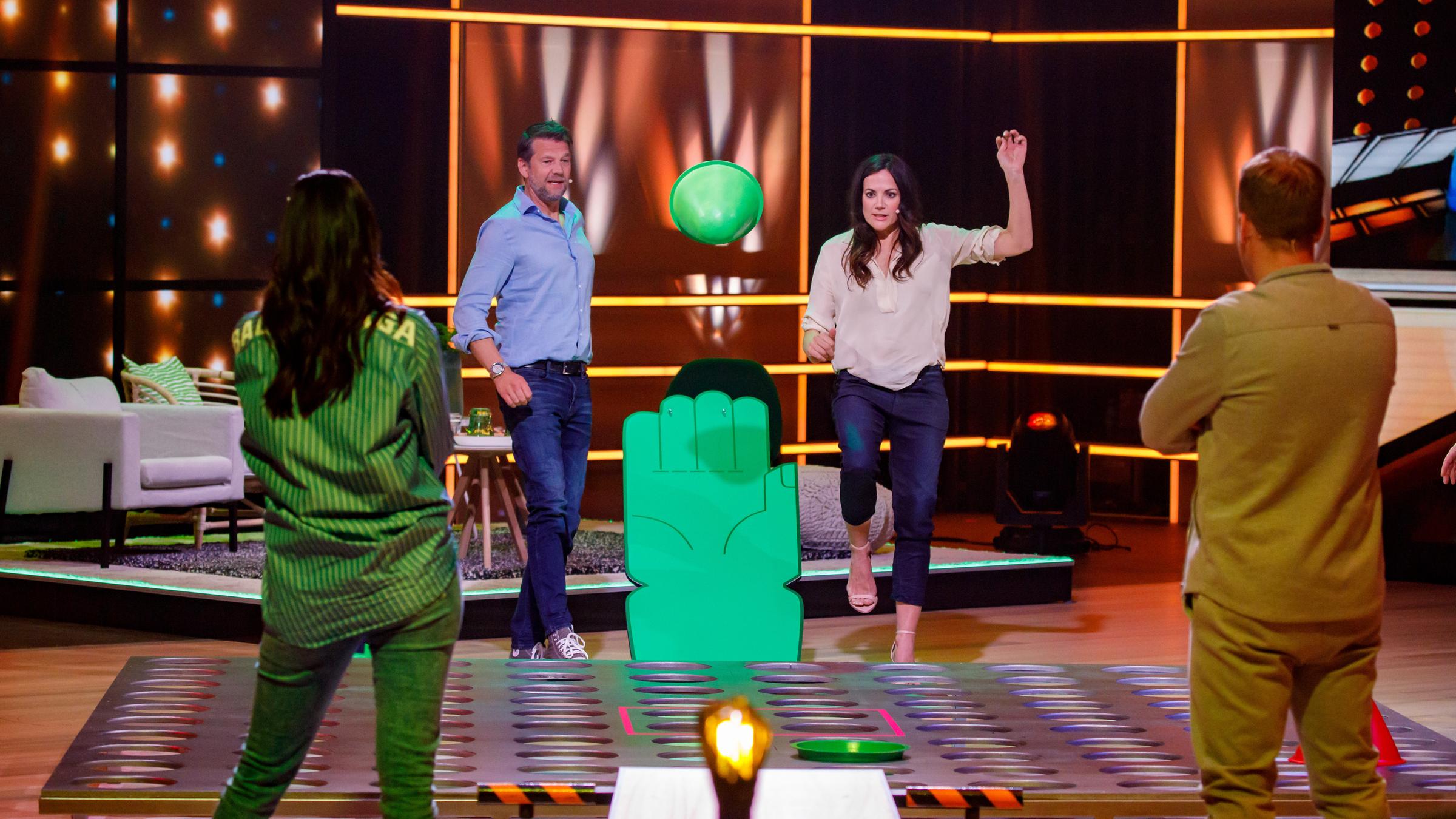 "Das Spiel beginnt!": Kai Wiesinger und Bettina Zimmermann spielen gegen Oliver Pocher und Amira Pocher. Sie spielen das Spiel "Hüpf, mein Hütchen!", dabei werden Hütchen mit Hilfe eines Katapultes auf eine Lochscheibe katapultiert.