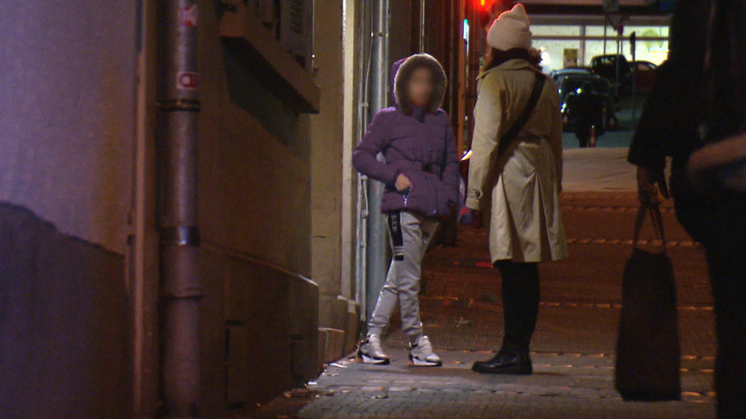 "37° Verratene Liebe - Die Masche der Loverboys": Zwei Frauen stehen sich auf einer Straße gegenüber. Die eine Frau steht mit dem Rücken zur Kamera. Sie reden miteinander. Es ist Abend.