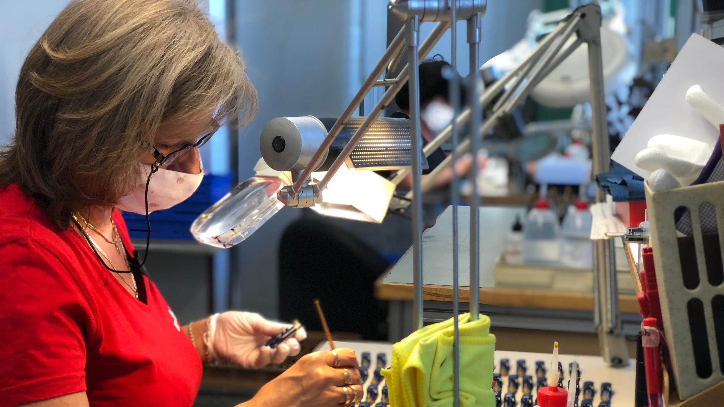 "plan b: Made in Germany - Sicher produzieren auch in Krisenzeiten": In einer Werkstatt. Eine Frau bemalt kleine Metallteile.