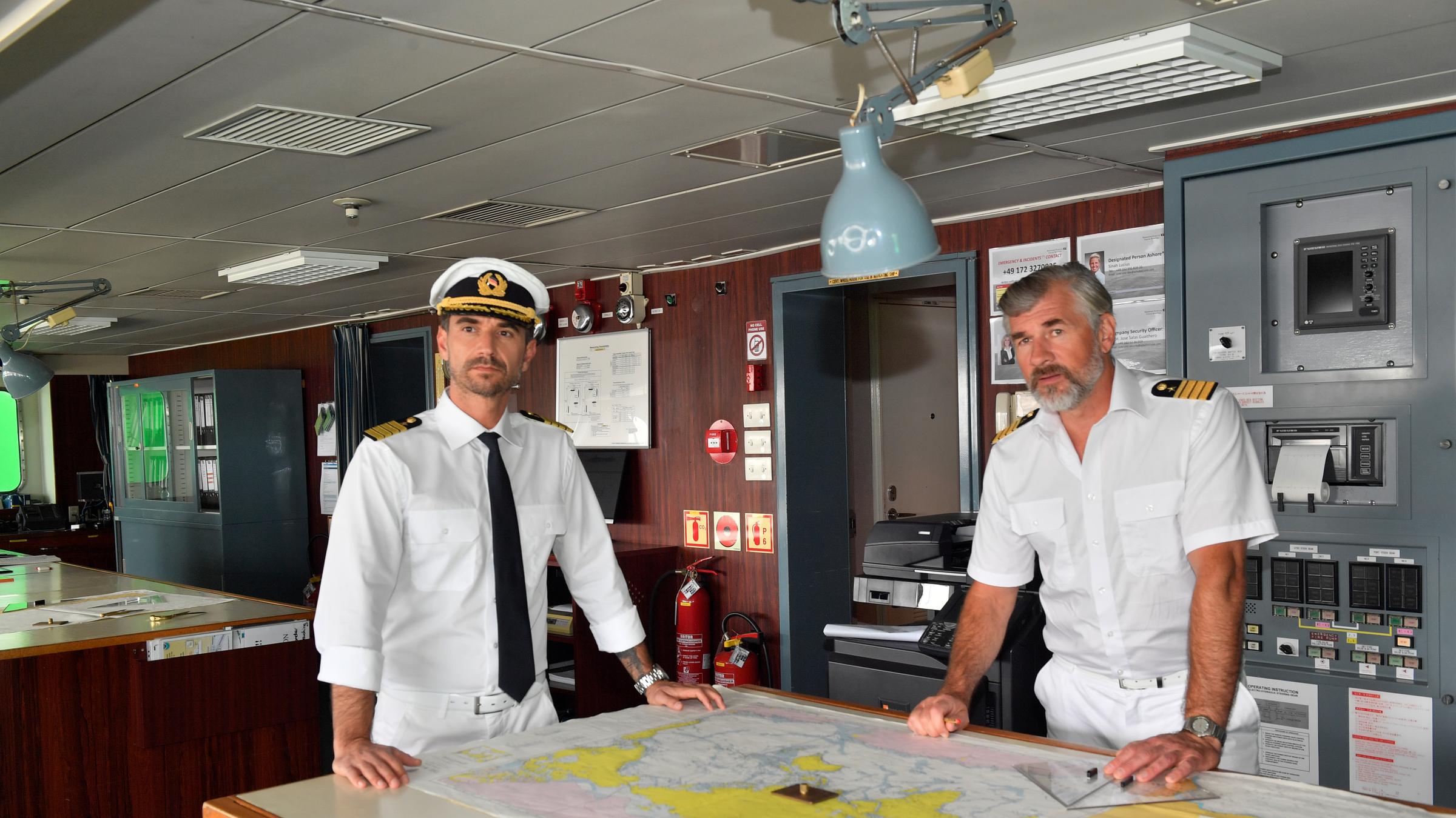 "Das Traumschiff: Kapstadt": Kapitän Max Parger (Florian Silbereisen) und Staff-Kapitän Martin Grimm (Daniel Morgenroth) stehen auf der Brücke des Schiffs. Vor ihnen liegt eine Karte ausgebreitet auf dem Tisch.