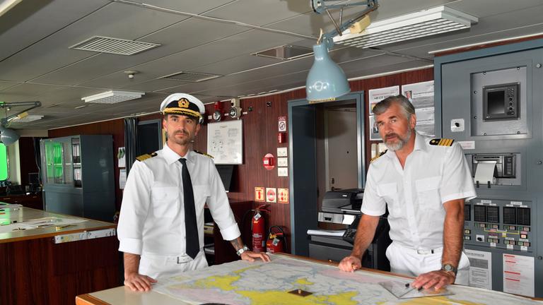 "Das Traumschiff: Kapstadt": Kapitän Max Parger (Florian Silbereisen) und Staff-Kapitän Martin Grimm (Daniel Morgenroth) stehen auf der Brücke des Schiffs. Vor ihnen liegt eine Karte ausgebreitet auf dem Tisch.