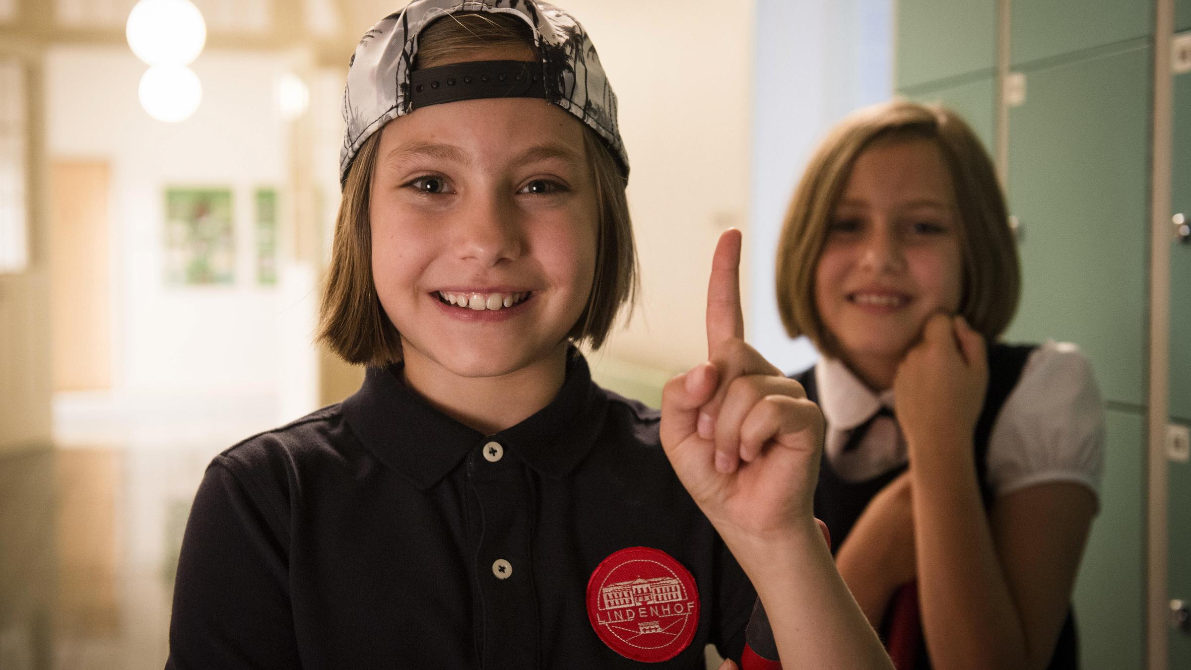 "Hanni & Nanni - Mehr als beste Freunde": Nanni Sullivan (Rosa Meinecke) mit erhobenen Zeigefinger und Hanni Sullivan (Laila Meinecke) im Hintergrund schauen in die Kamera.