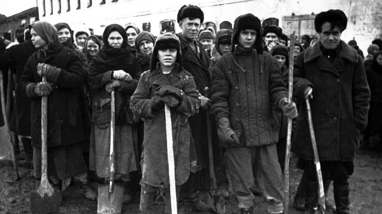  "Hitlers Sklaven - Die Geschichte der NS-Zwangsarbeiter - Vernichtung": Schwarz-Weiß-Foto. Das Bild zeigt eine Gruppe von russischen Zwangsarbeitern.