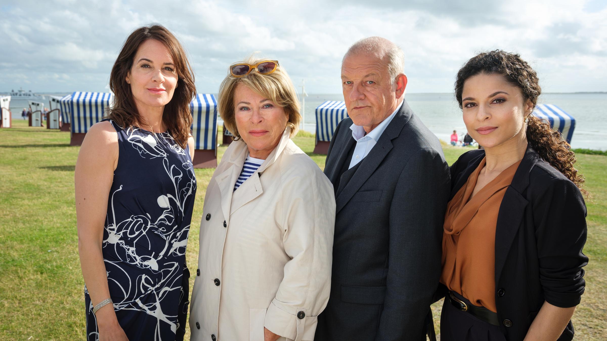 "Wilsberg - Wellenbrecher": Tanja Steinthal (Stephanie Eidt), Anna Springer (Rita Russek), Georg Wilsberg (Leonard Lansink) und Dr. Tessa Tilker (Patricia Meeden) stehen nebeneinander am Meer und schauen in die Kamera.