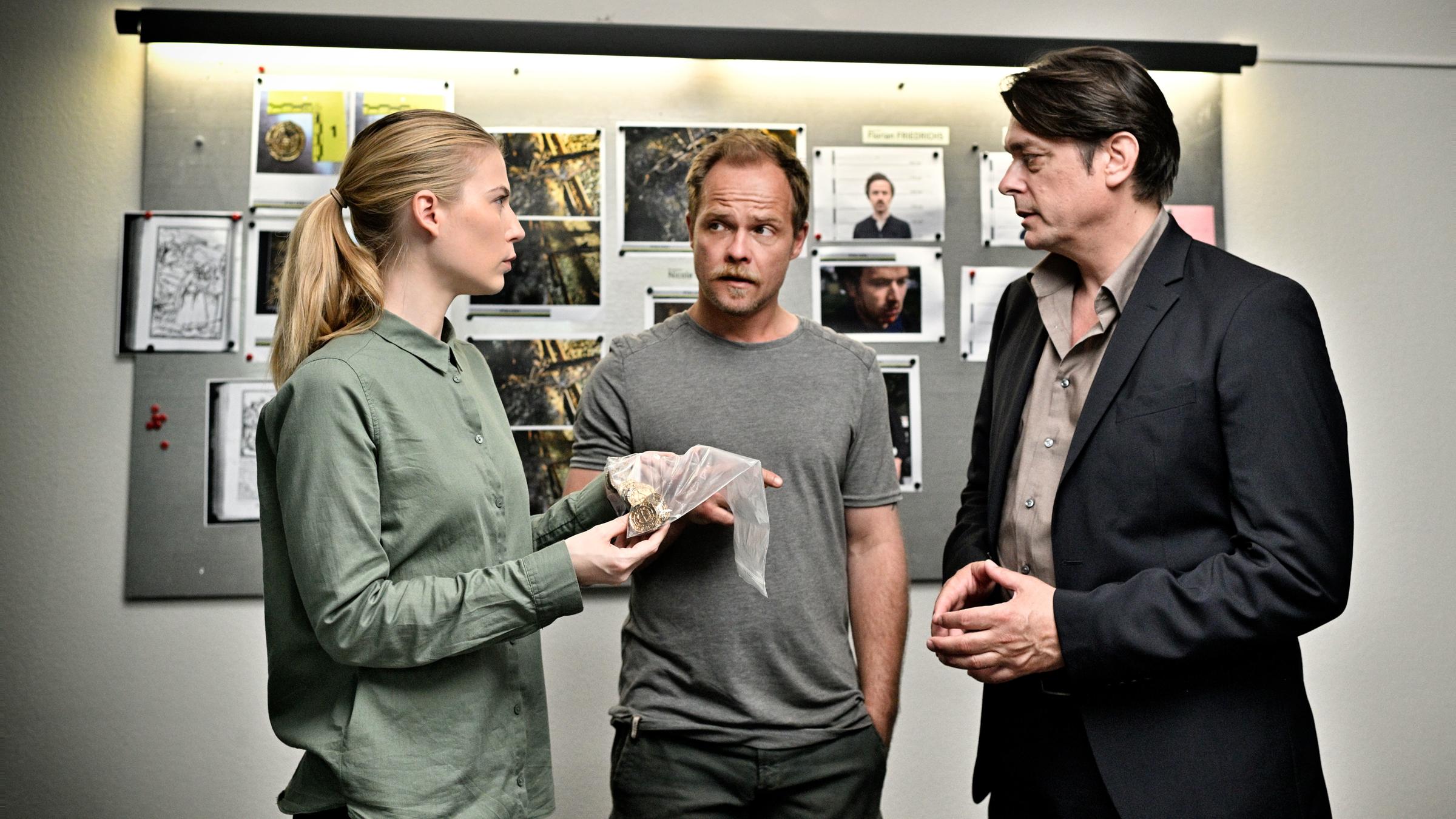 „Die Toten vom Bodensee - Fluch aus der Tiefe“: Hannah Zeiler (Nora Waldstätten), Michael Oberländer (Matthias Koeberlin) und Thomas Komlatschek (Hary Prinz) stehen im Büro beieinander und besprechen sich. Hannah hält einen Asservatenbeutel in ihren Händen.