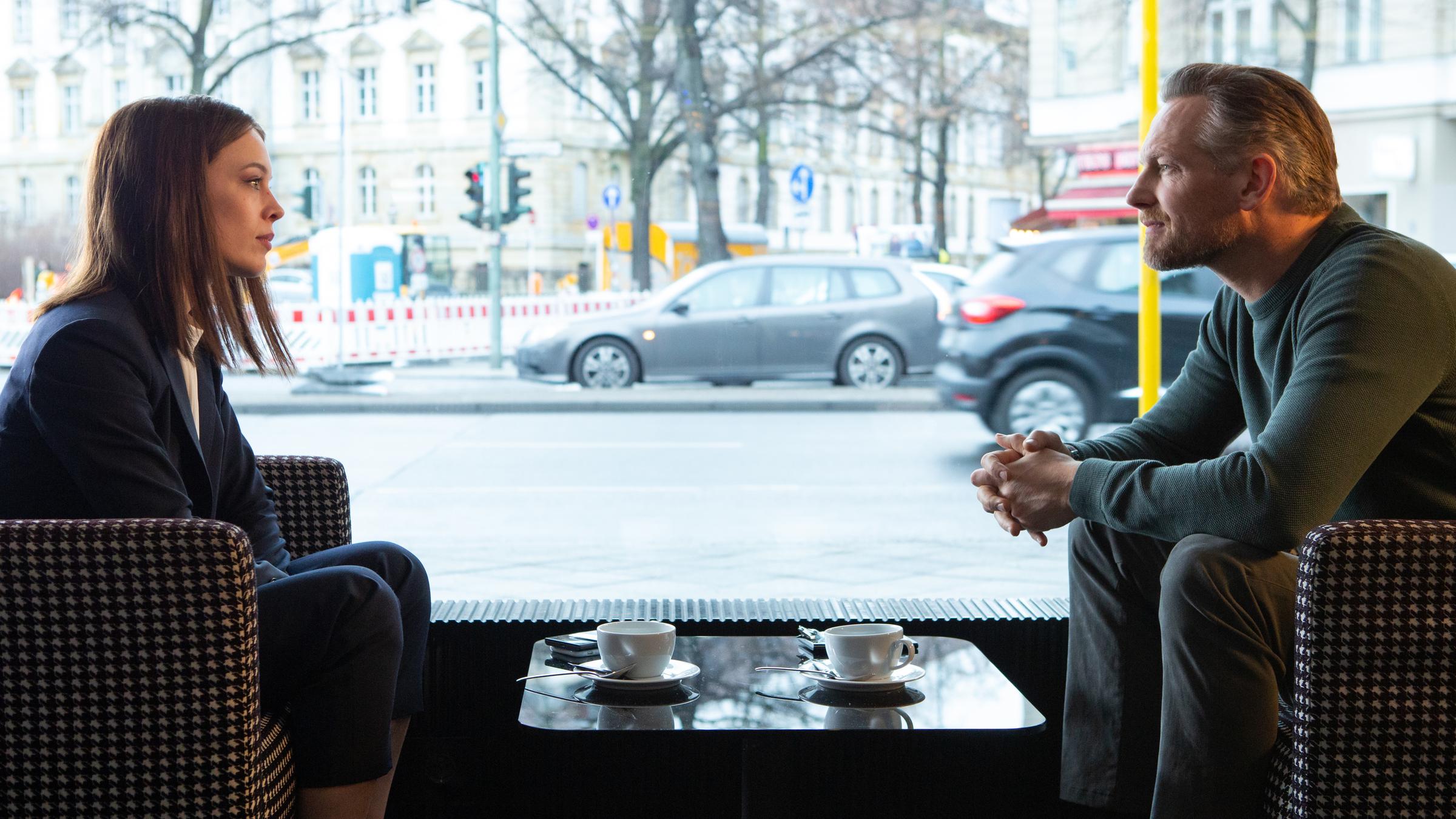 "Bad Banks II": Jana Liekam (Paula Beer) und Gabriel Fenger (Barry Atsma) sitzen sich in einem Café gegenüber und schauen sich an.