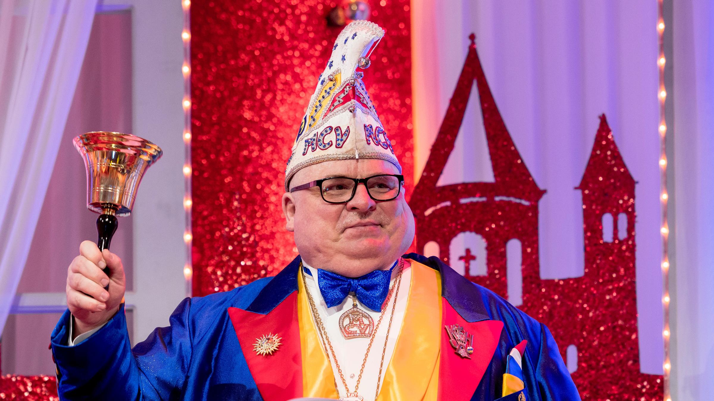 "Mainz bleibt Mainz, wie es singt und lacht": Sitzungspräsident Andreas Schmitt mit Narrenkappe und buntem Frack schwingt die Sitzungsglocke.