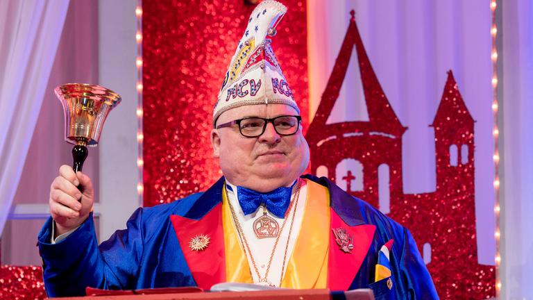 "Mainz bleibt Mainz, wie es singt und lacht": Sitzungspräsident Andreas Schmitt mit Narrenkappe und buntem Frack schwingt die Sitzungsglocke.