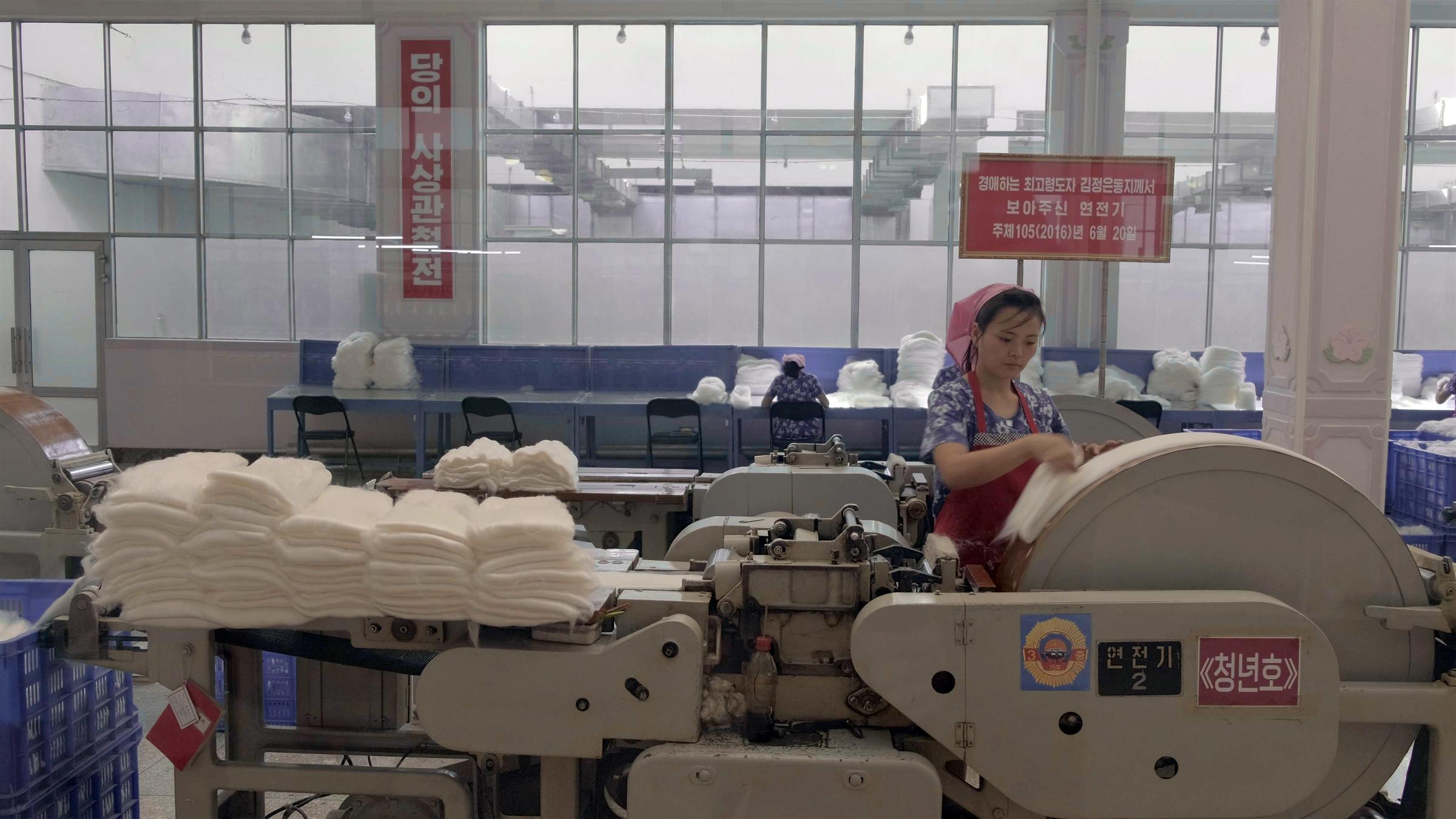 "Büro 39 - Nordkoreas schwarze Kassen": Textilarbeiterin mit Kopftuch an einer Maschine.