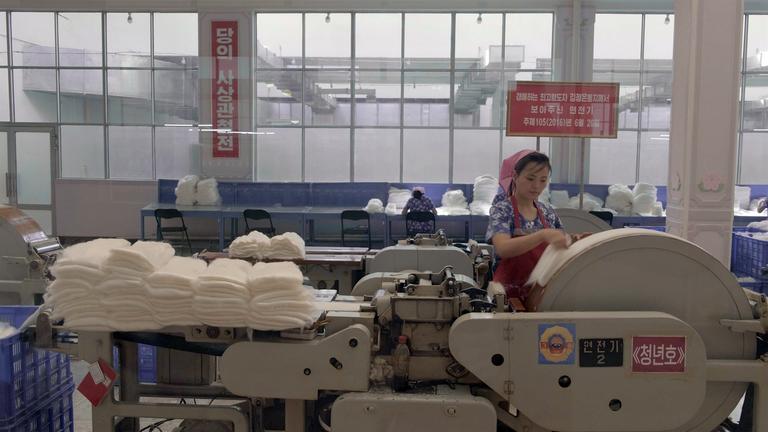 "Büro 39 - Nordkoreas schwarze Kassen": Textilarbeiterin mit Kopftuch an einer Maschine.