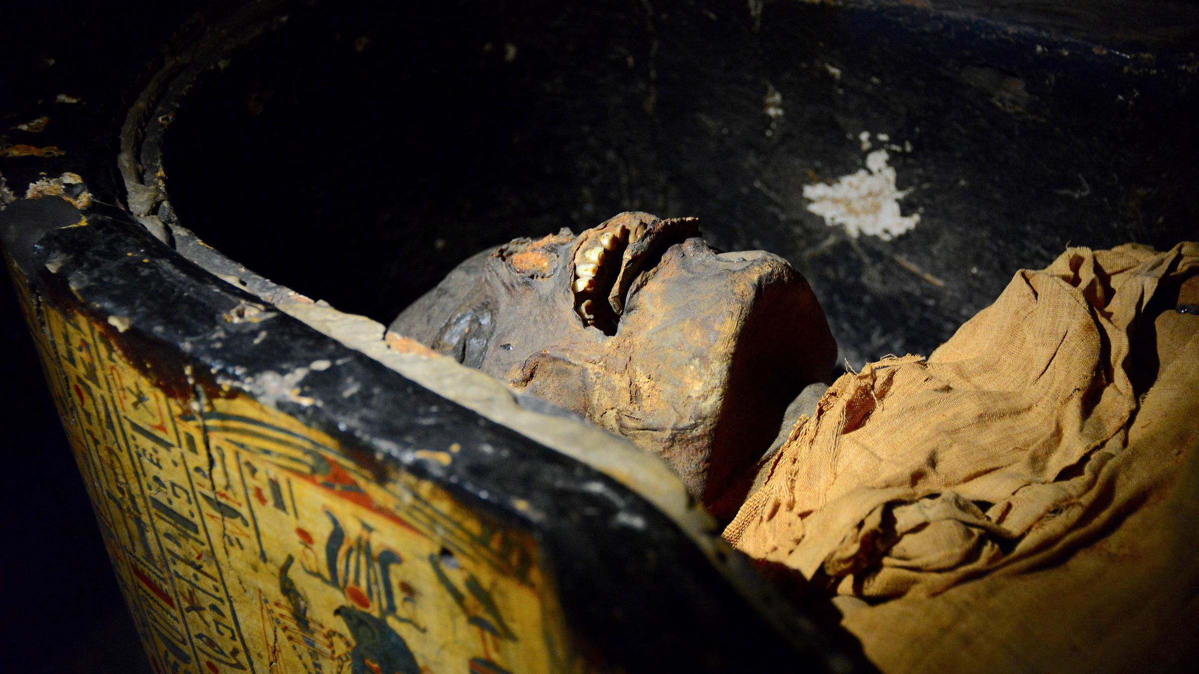 "Terra X: Ungelöste Fälle der Archäologie - Mumien": Eine menschliche Mumie liegt in einem innen schwarz gefärbten und außen mit altägyptischen Bildern verzierten Sarkophag.