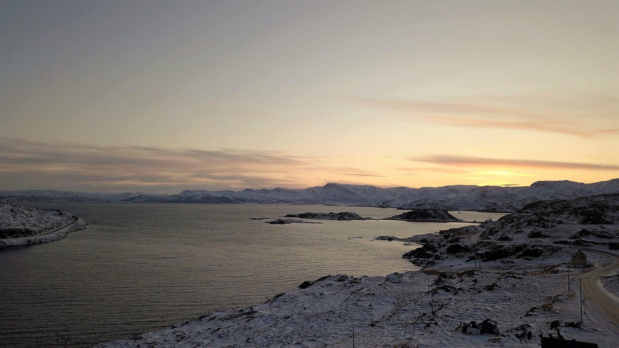 "Nordlichter - Leben am Polarkreis (1) - Von Spitzbergen bis Ostsibirien": Wasser, umgeben von schneebedeckter Fjörd-Landschaft bei Sonnenuntergang.