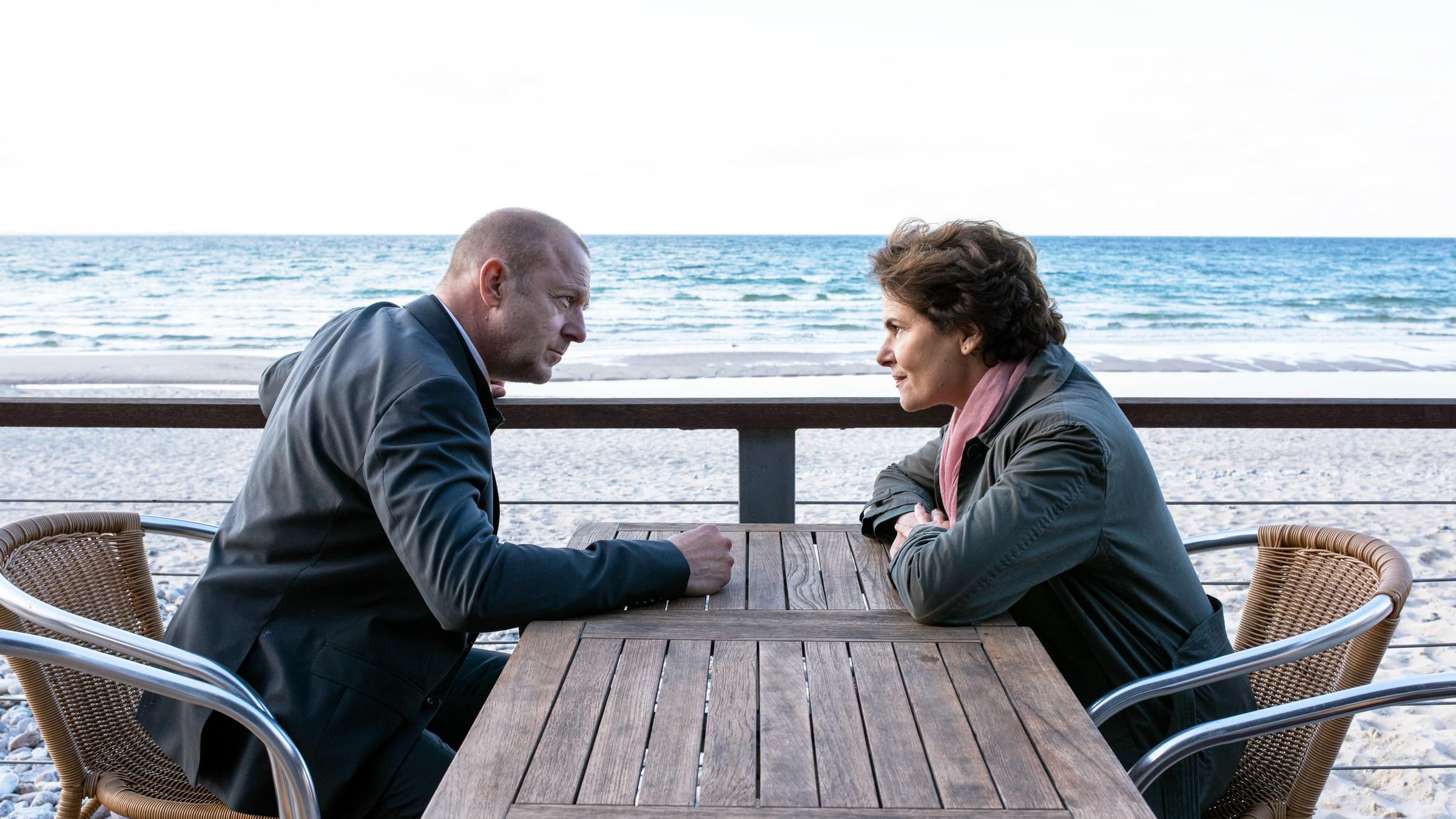 "Das Mädchen am Strand (1)": Kessler (Heino Ferch) und Hella (Barbara Auer) sitzen an einem Tisch am Strand und unterhalten sich.