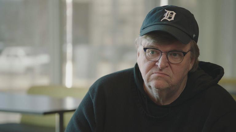 "Fahrenheit 11/9 von Michael Moore": Nahaufnahme von Michael Moore. Er trägt eine schwarze Base-Cap und eine schwarze Kapuzenjacke.
