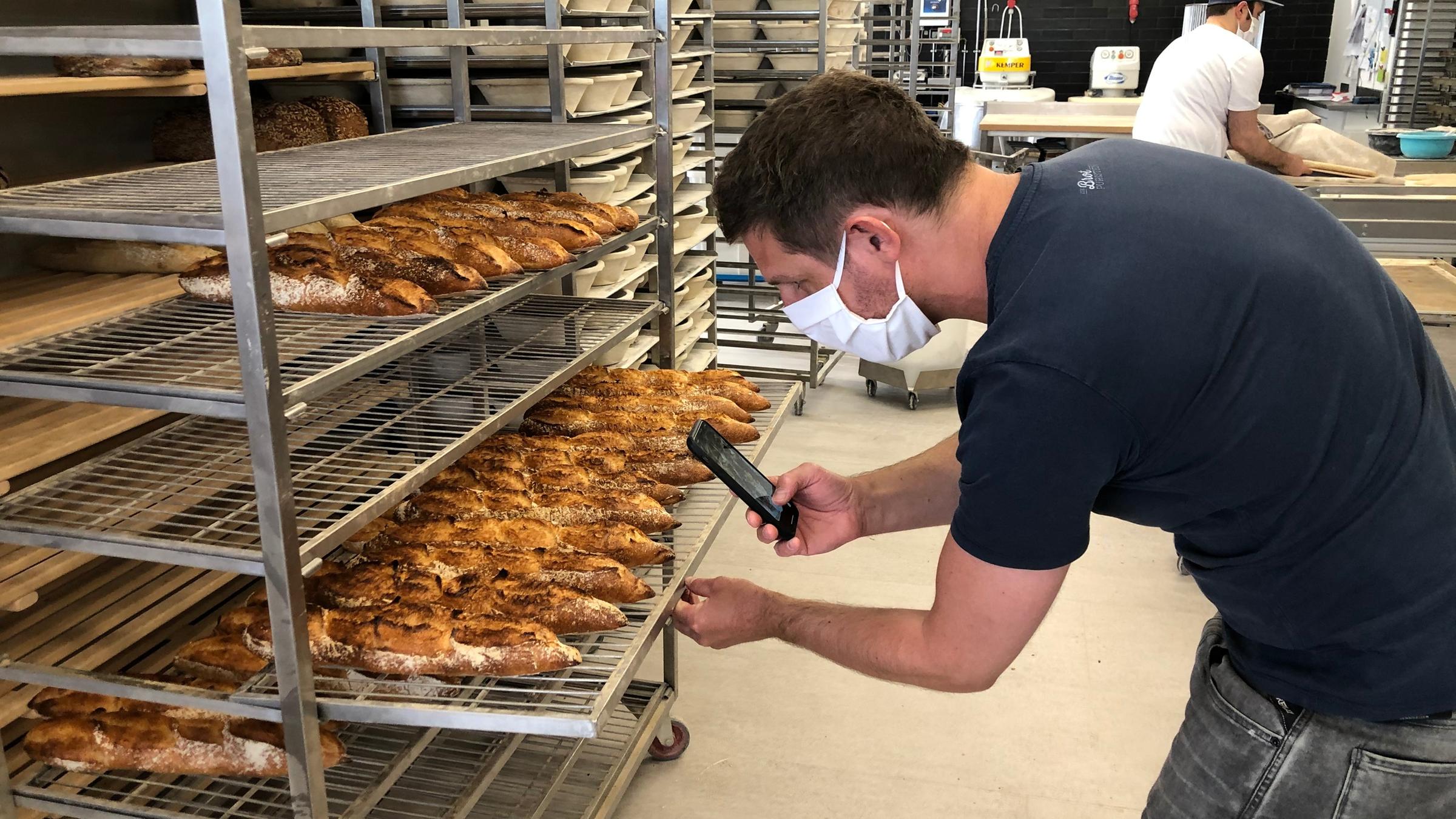 "ZDF.reportage: Die neuen Macher - Aufbruch im Handwerk": Bäcker Sebastian Däuwel fotografiert mit dem Handy die frisch gebackenen Baguette-Brote.