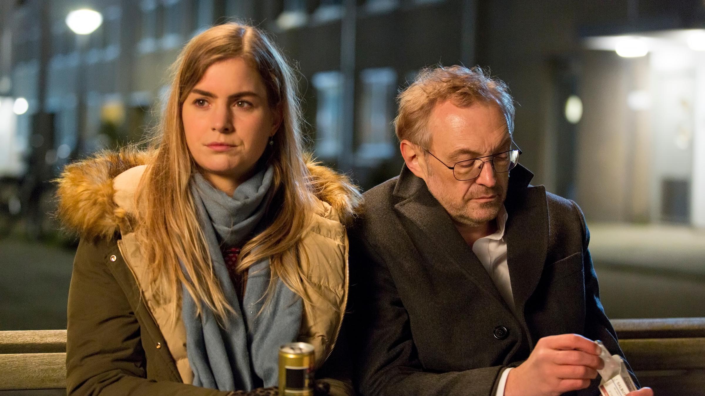 "Arthur & Claire": Arthur (Josef Hader) und Claire (Hannah Hoekstra) sitzen in nächtlicher Stunde dicht nebeneinander auf einer Bank.