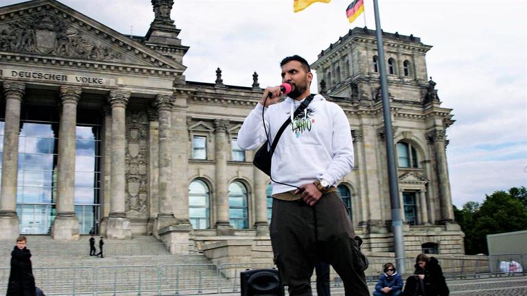 "ZDFzoom: Die Macht der Corona-Mythen - Gefahr für die Demokratie?": Attila Hildmann steht vor dem Reichstagsgebäude und spricht in ein Mikrofon.