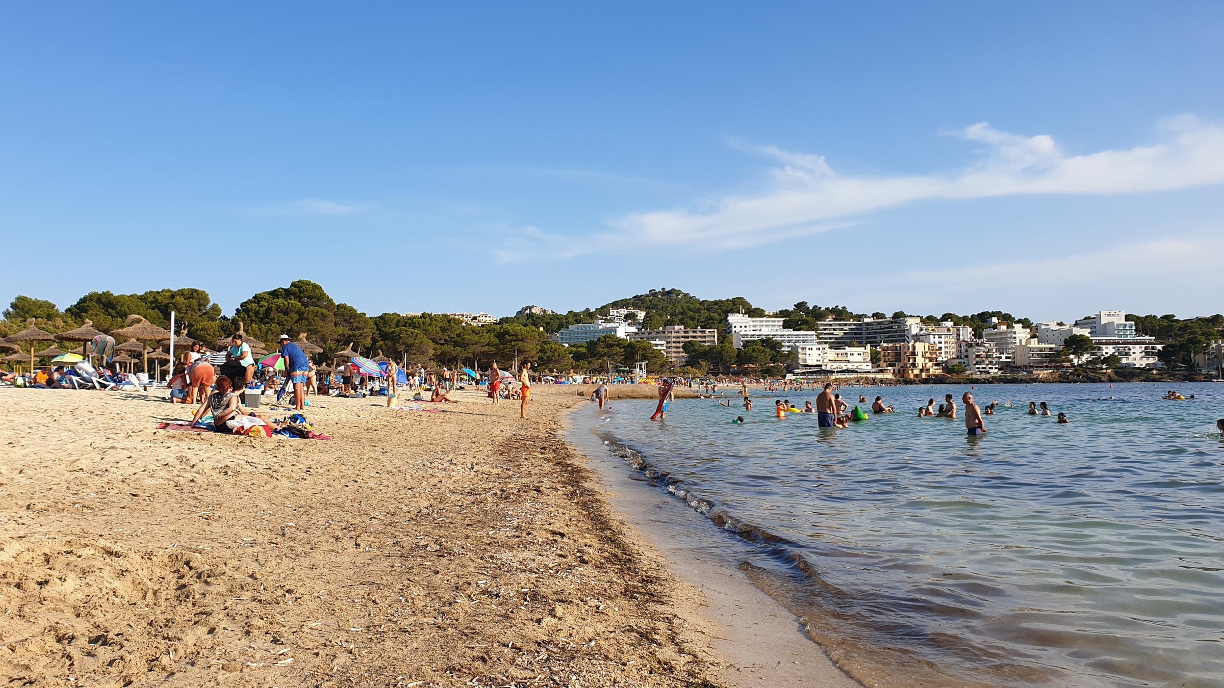 "ZDF.reportage: Mit Maske nach Mallorca - Das neue Urlaubsgefühl": Ein Strand mit Urlaubern. Einige sitzen am Strand, andere sind im Meer.