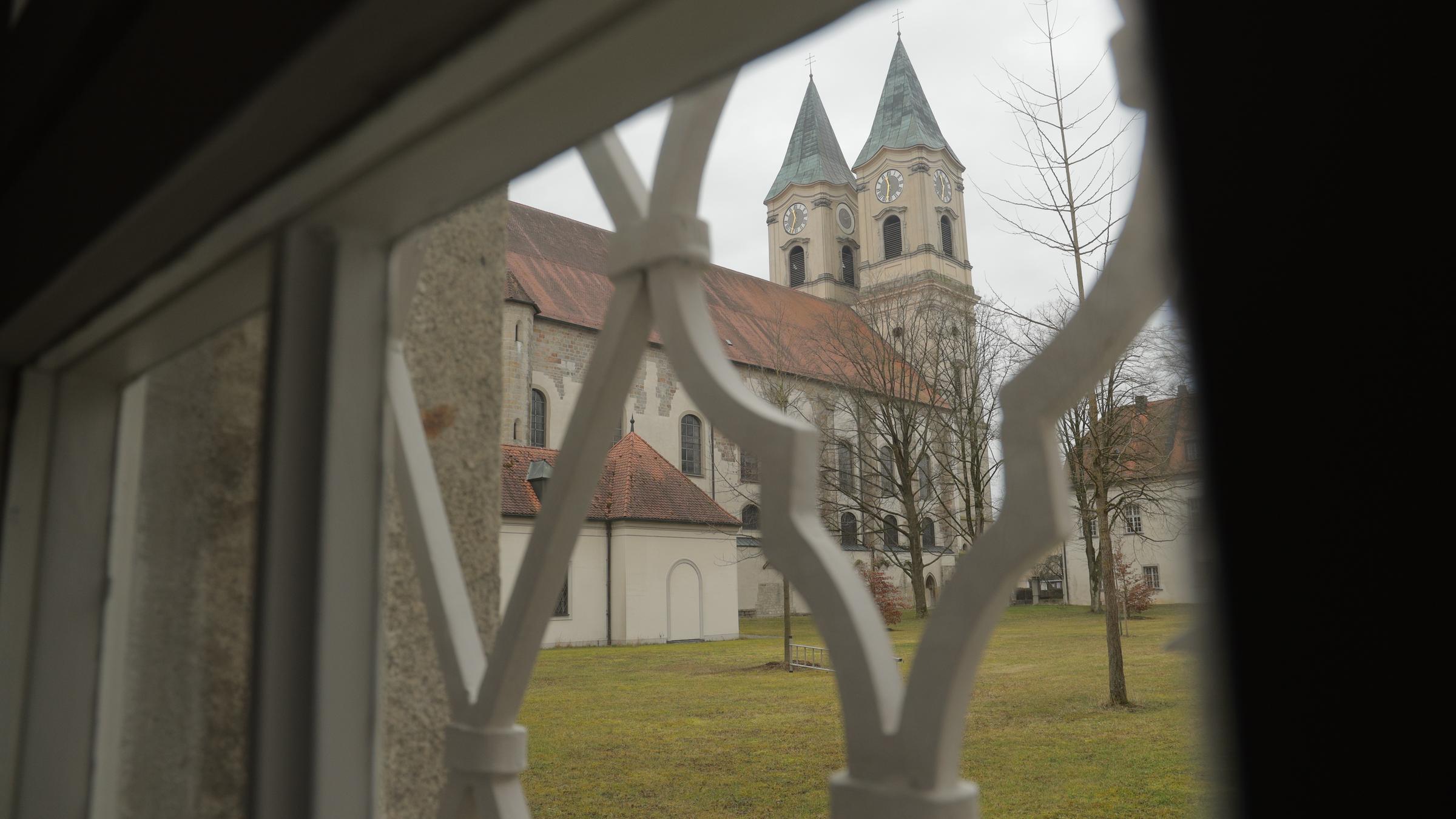 "Sehnsuchtsort Kloster": Blick durch ein Fenster auf den Innenhof und die Kirche des Klosters Niederaltaich.