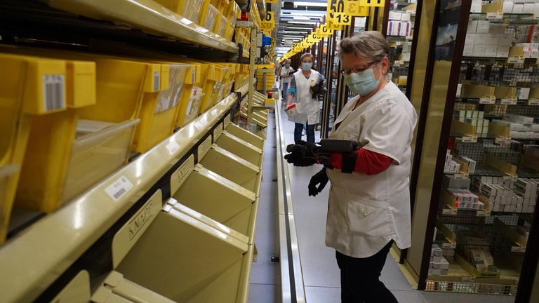 "planet e. pandemie: Wie die Globalisierung sich verändert": Blick in eine Verteilstation für Medikament mit drei mit Mund-Nasen-Schutz ausgestattete Mitarbeiterinnen bei der Verteilarbeit.
