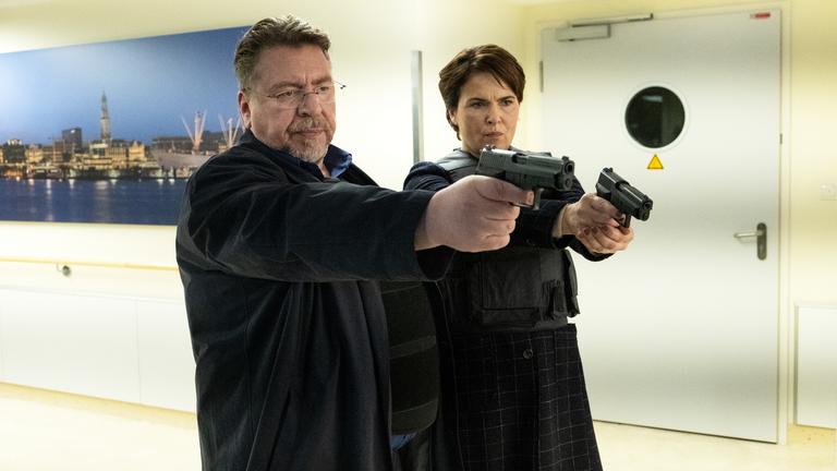 "Nachtschicht - Cash & Carry": Erichsen (Armin Rohde) und Lisa (Barbara Auer) stehen in einem Krankenhausflur. Sie richten ihre Waffen auf eine Person, die nicht im Bild ist.
