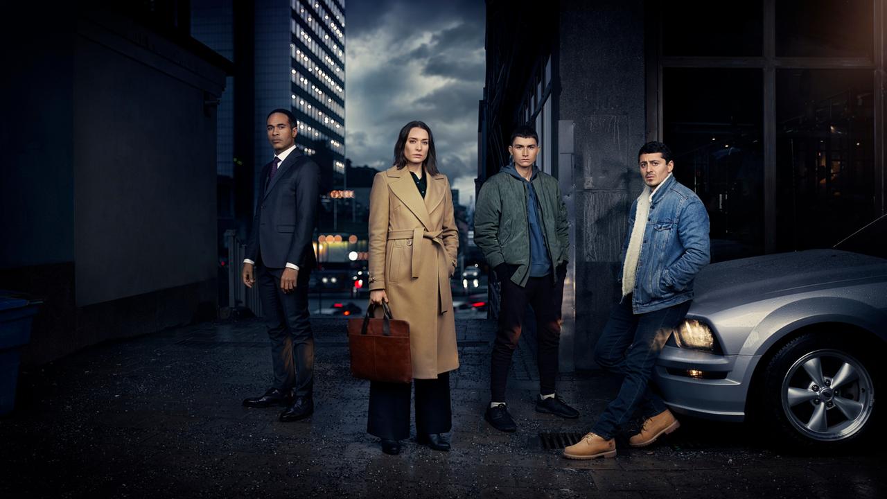 "Hidden Agenda": Magnus (Peter Gardiner), Emily (Josefin Asplund), Nicola (Gustav Lindh) und Teddy (Alexej Manvelov) posieren nachts auf einer Straße. Rechts im Bild ist die Kühlerhaube eines silbernen Autos zu sehen.