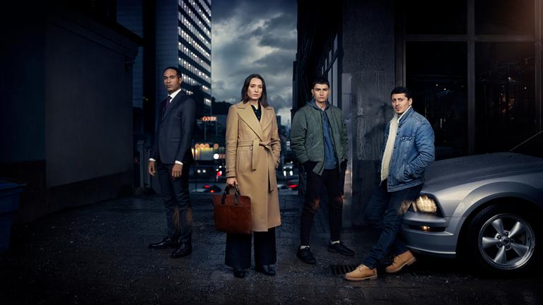"Hidden Agenda": Magnus (Peter Gardiner), Emily (Josefin Asplund), Nicola (Gustav Lindh) und Teddy (Alexej Manvelov) posieren nachts auf einer Straße. Rechts im Bild ist die Kühlerhaube eines silbernen Autos zu sehen.