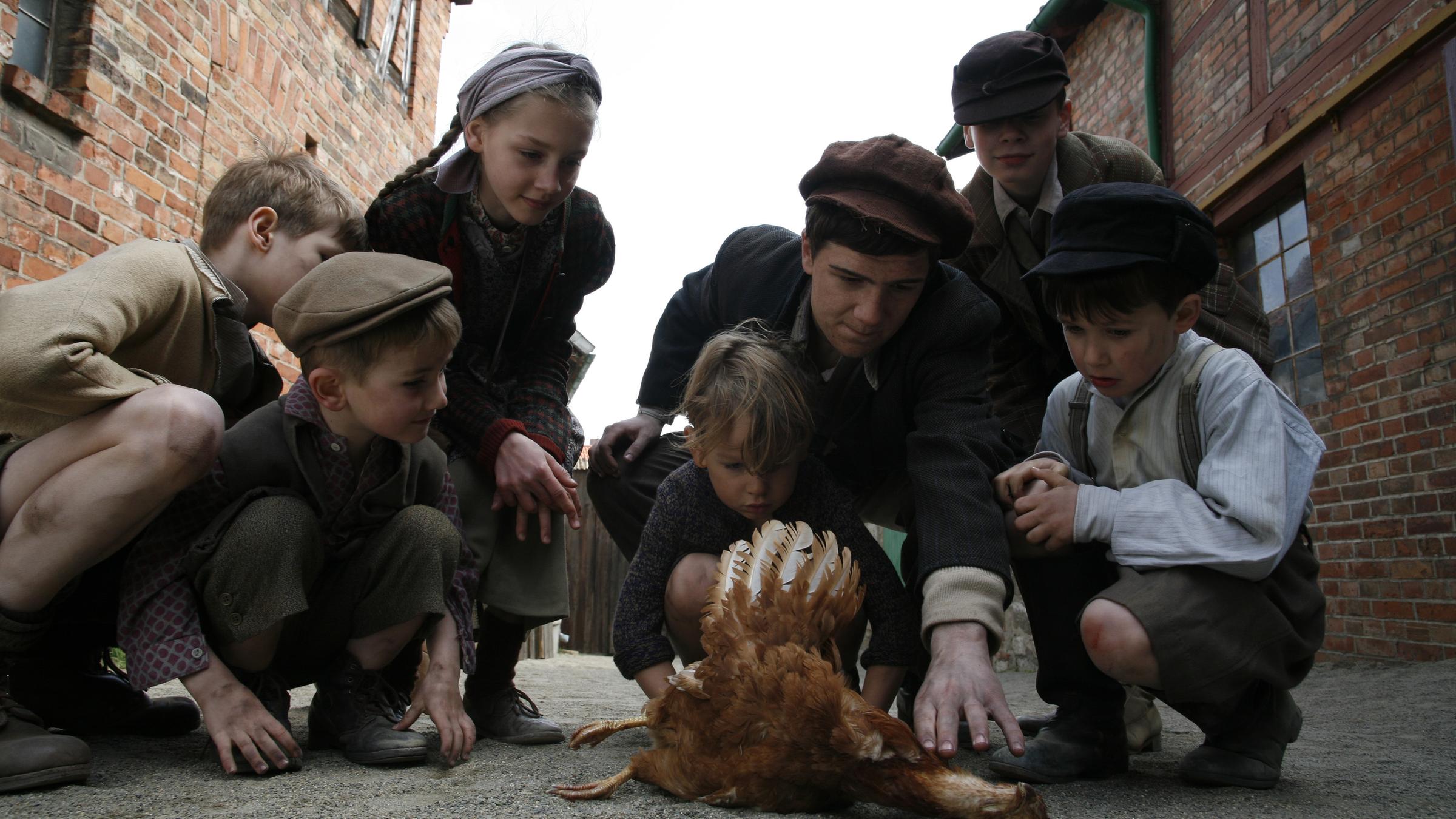 "Ein Dorf schweigt": Kinder kauern um ein totes Huhn herum.
