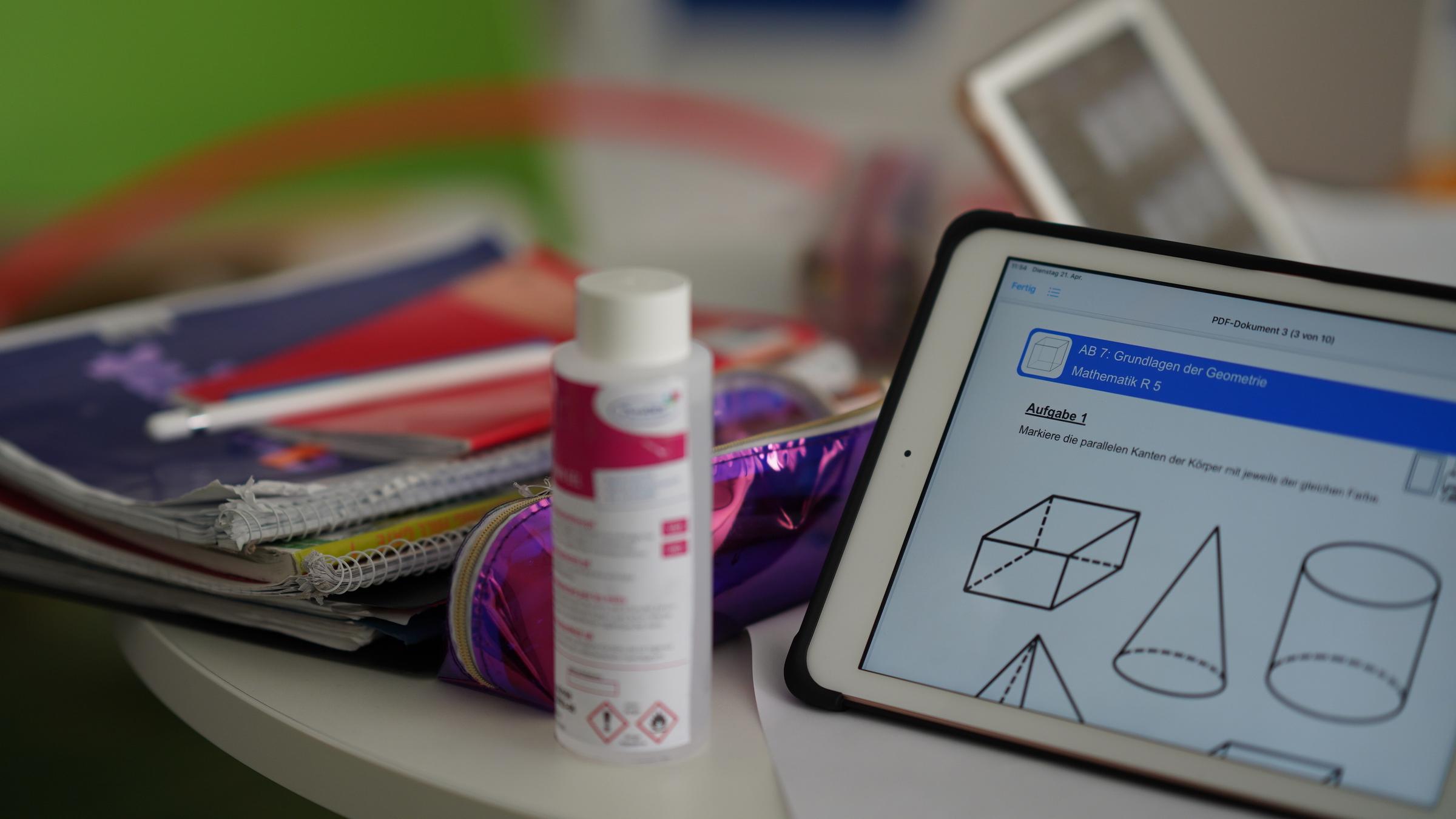 "ZDFzoom: Schulen im Corona-Stress - Lernen aus der Krise": Tisch mit Heften, Tablett und einer Flasche Desinfektionsmittel.