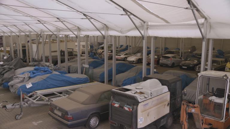 "ZDF.reportage: Letzte Rettung Pfandleihhaus": Zum Teil verstaubte Autos, Boote und ein Bagger stehen in der Garage eines Pfandleihhauses.