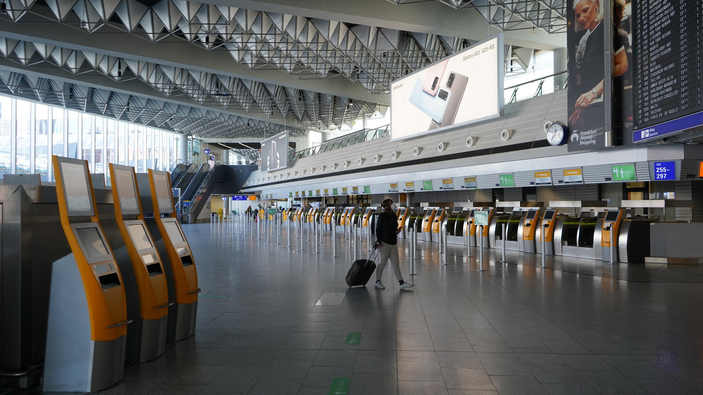 "Airlines am Boden - Luftfahrt in der Corona-Krise": Eine Frau geht mit ihrem Koffer durch das ansonsten menschenleere Terminal 1 des Frankfurter Flughafens.
