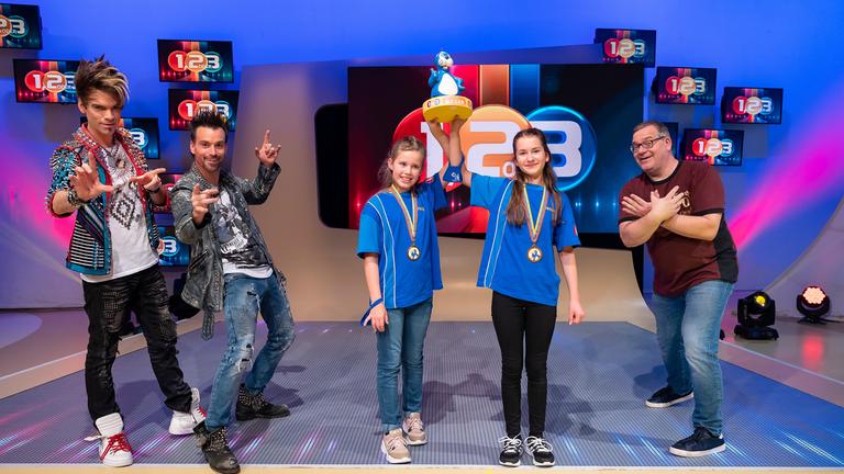 "1, 2 oder 3 - Elton & Friends": Die Kandidatinnen aus Bernau/Deutschland halten gemeinsam den Piet-Flosse-Pokal in die Höhe. Links von ihnen stehen die Ehrlich Brothers und rechts Moderator Elton.