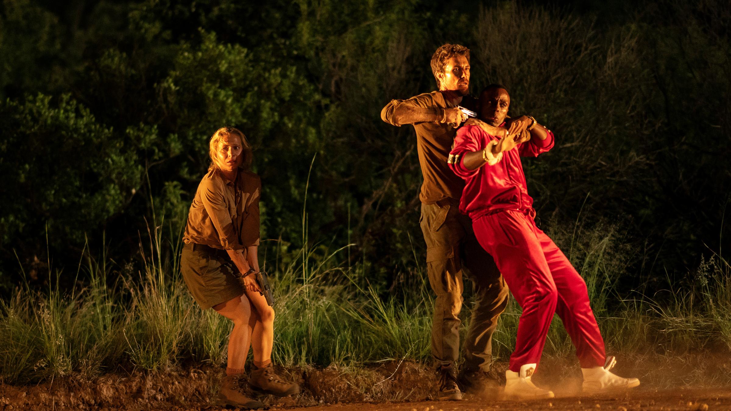 "Trackers - Rote Spur": Flea (Trix Vivier) steht neben Lemmer (James Gracie). Inkunzi (Sisanda Henna) wird von Lemmer festgehalten und mit einer Waffe bedroht. Doch sie drehen den Spieß um.