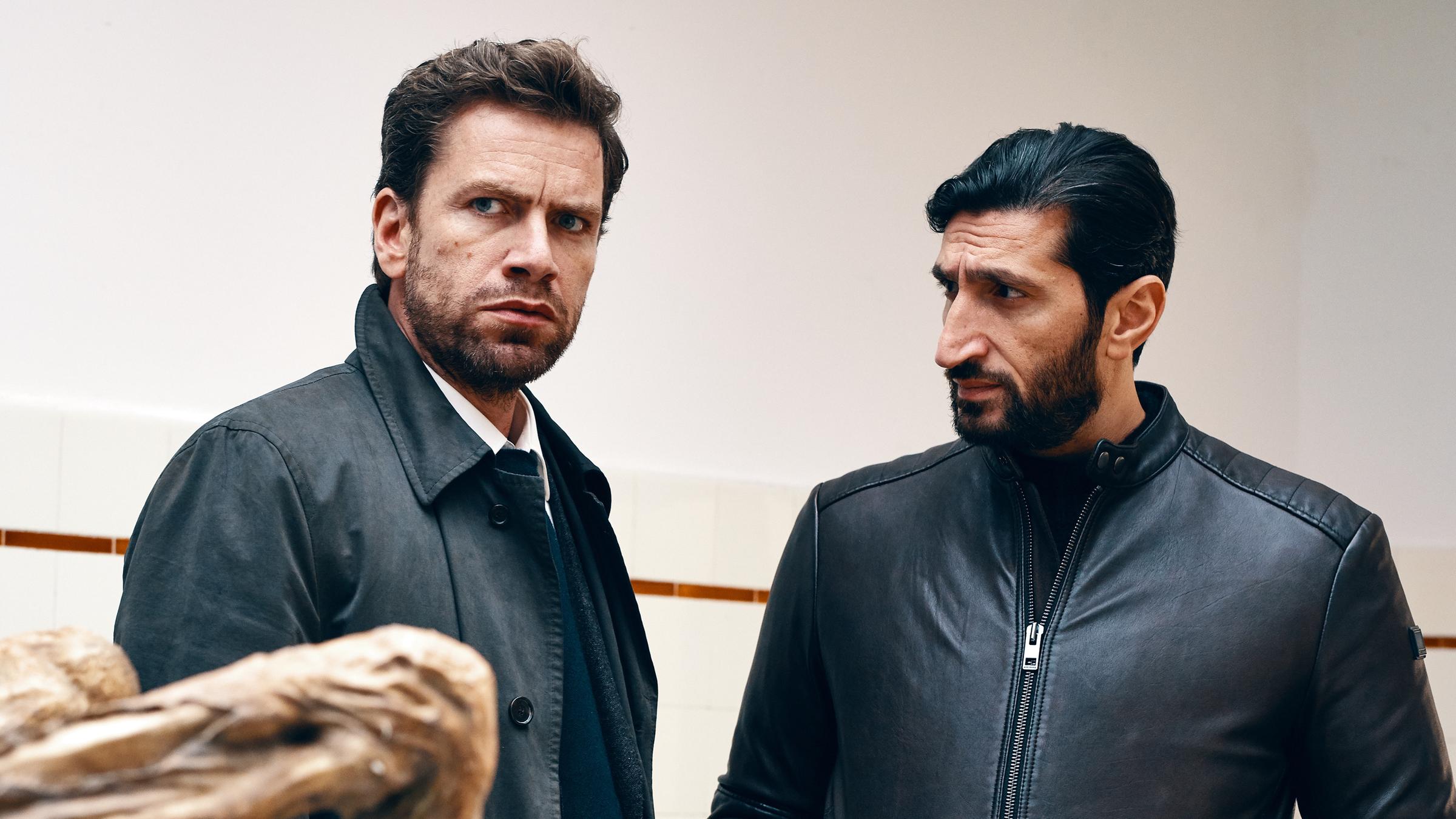 "Jussi Adler-Olsen: Verachtung": Assistent Assad (Fares Fares) steht neben Kommissar Carl Mørck (Nikolaj Lie Kaas) und sieht ihn an. Carl sieht nach vorn..