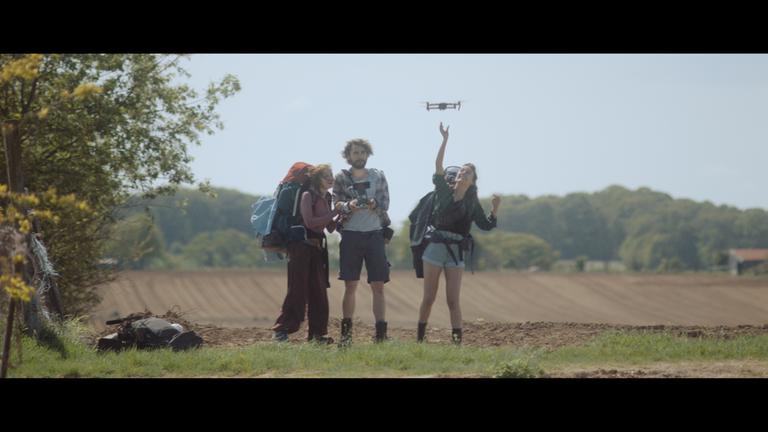 "Missing Lisa - Freigeister": Ylena (Laurian Callebaut), Michiel (Boris Van Severen) und Zoë (Violet Braeckman) stehen nebeneinander auf einem Feld. Zoë lässt eine Drohne steigen.
