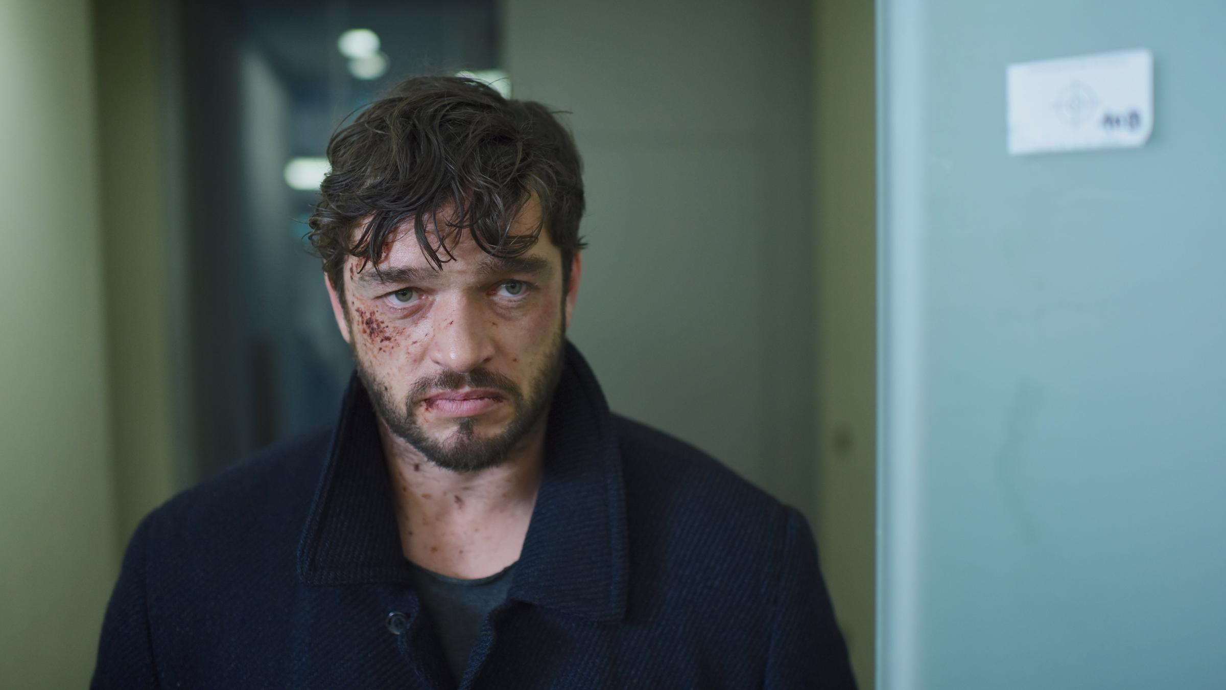 "Das Ende der Wahrheit": Martin Behrens (Ronald Zehrfeld) steht zerzaust und mit Blutkrusten in Gesicht frontal zur Kamera.