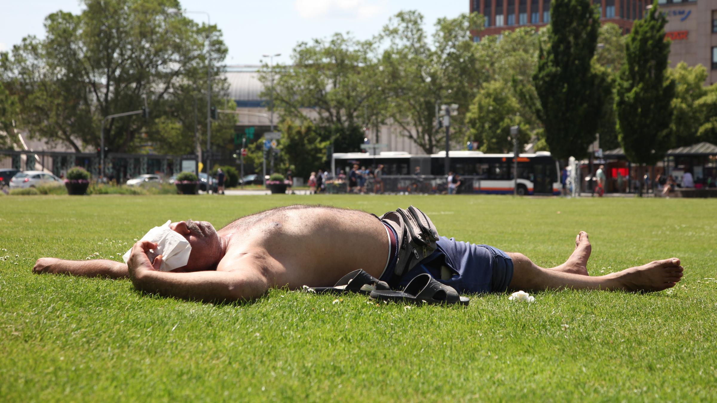 "planet e.: Hitzefalle Stadt - Wenn es tropisch wird": Mann mit nacktem Oberkörper liegt auf einer grünen Wiese.