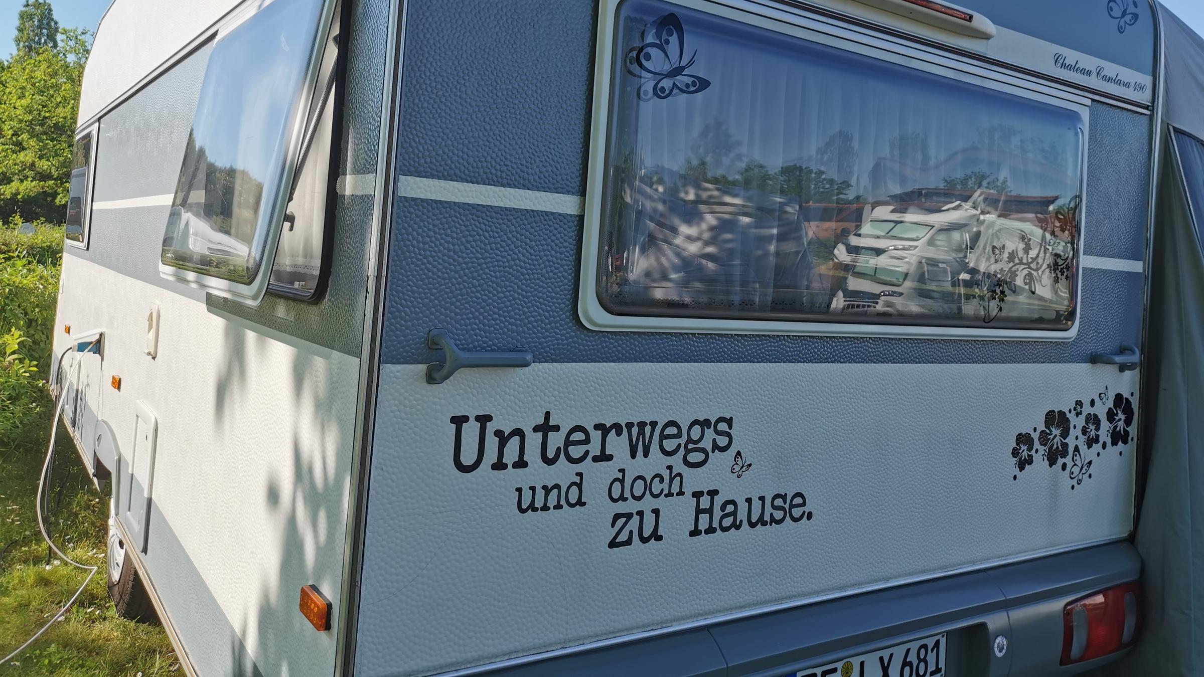"ZDF.reportage: Große Freiheit Wohnmobil - Camper legen los": Die Rückseite eines Wohnwagens, unten in geschwungener Aufschrift "Unterwegs und doch zu Hause".