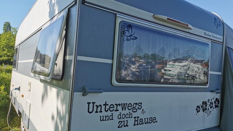 "ZDF.reportage: Große Freiheit Wohnmobil - Camper legen los": Die Rückseite eines Wohnwagens, unten in geschwungener Aufschrift "Unterwegs und doch zu Hause".