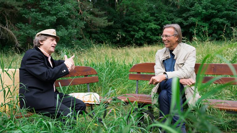 "Beim Pelzig auf der Bank - Scheiß Corona": Erwin Pelzig und Harald Welzer sitzen sich im Grünen auf Bänken gegenüber und diskutieren.