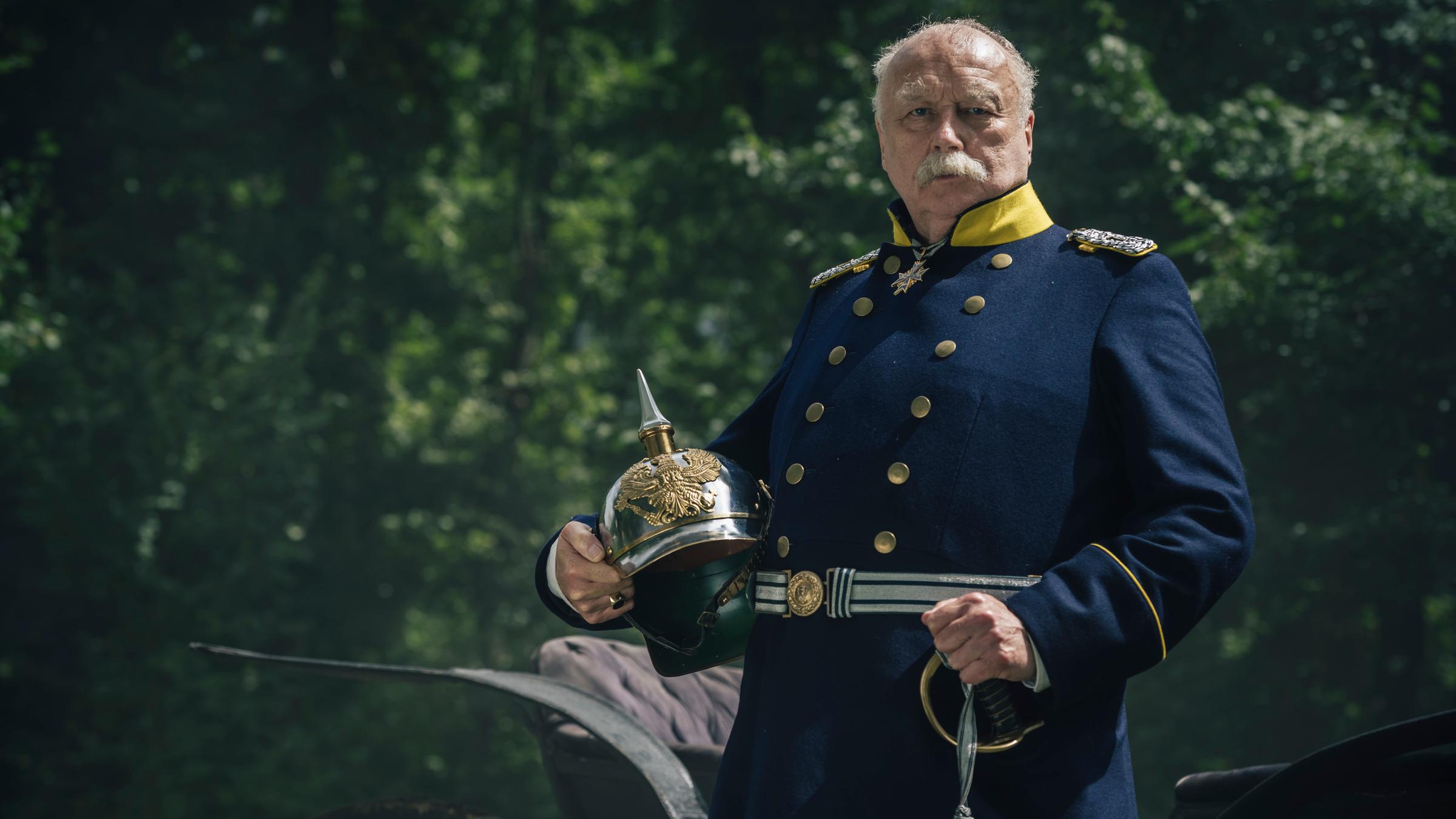 "Kaiserspiel": Spielszene: Otto von Bismarck (Thomas Thieme) in Uniform, im rechten Arm hält er seinen Helm.