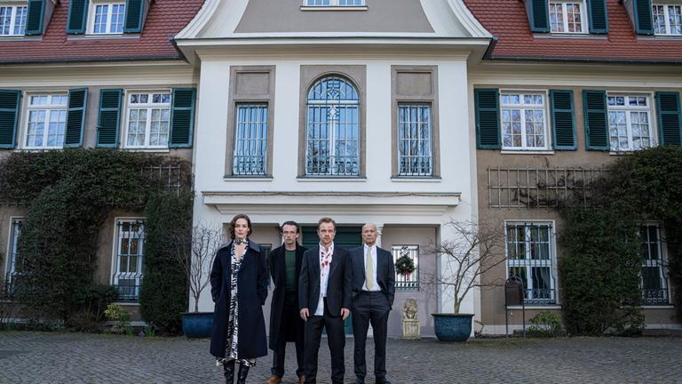 "Mord in der Familie - Der Zauberwürfel": Marianne Becker (Katharina Lorenz) steht zusammen mit Eric Becker (Lucas Gregorowicz), Thomas Becker (Matthias Koeberlin) und Henry Becker (Heiner Lauterbach) vor der Villa der Familie Becker. Es ist eine herrschaftliche Villa mit vielen Fenstern.