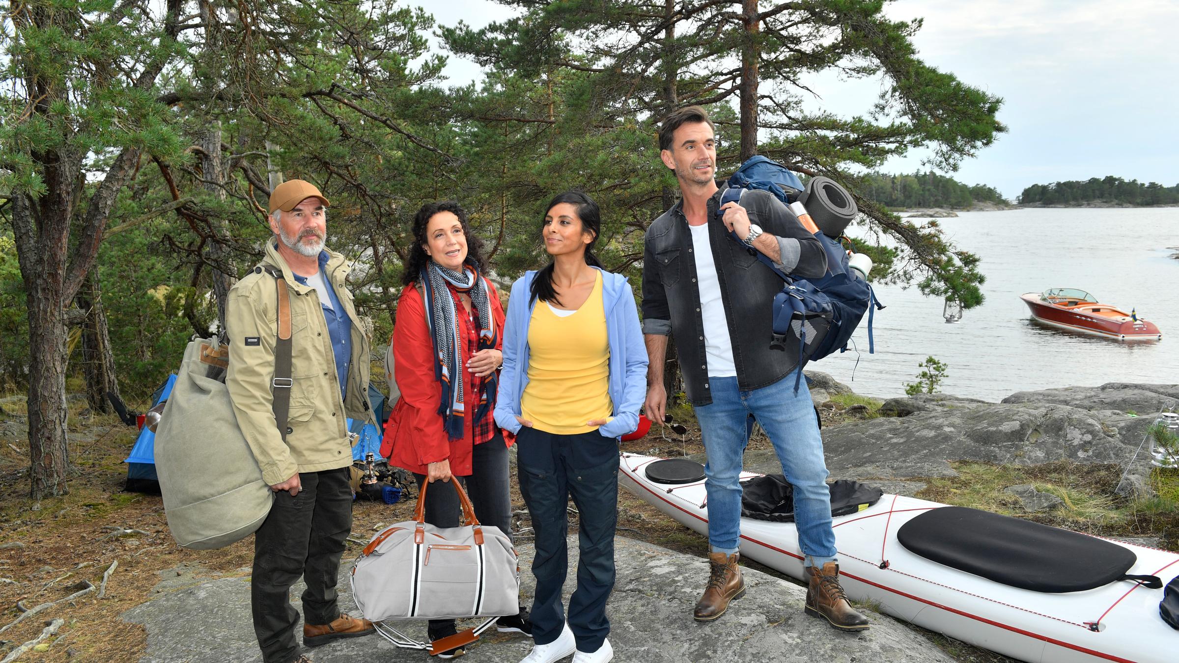 "Das Traumschiff: Schweden": Am See liegt ein Paddelboot. Daneben stehen im Freizeitdress Max Parger (Florian Silbereisen), Dr. Jessica Delgado (Collien Ulmen-Fernandes), Hanna Liebhold (Barbara Wussow) und Martin Grimm (Daniel Morgenroth). Sie tragen Reisetaschen und Rucksäcke. Im Hintergrund: Ein Waldgebiet um den See.