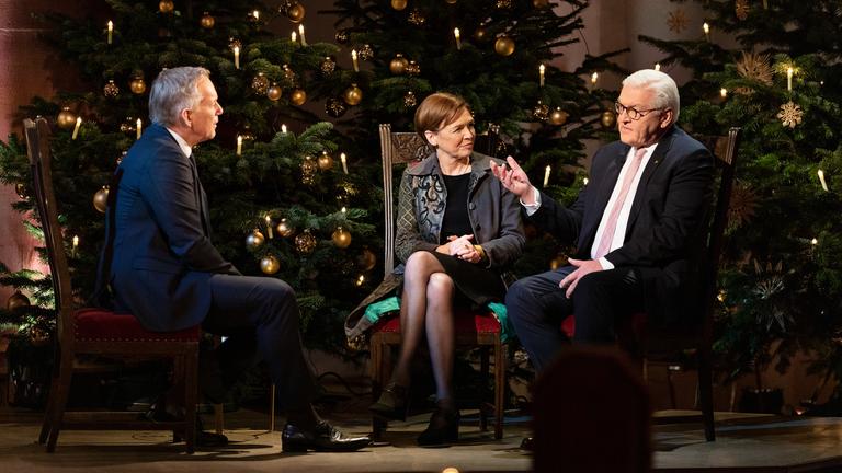 "Weihnachten mit dem Bundespräsidenten": Johannes B. Kerner, Elke Büdenbender, Frank-Walter Steinmeier im Gespräch, sitzend vor zwei geschmückten Weihnachtsbäumen.