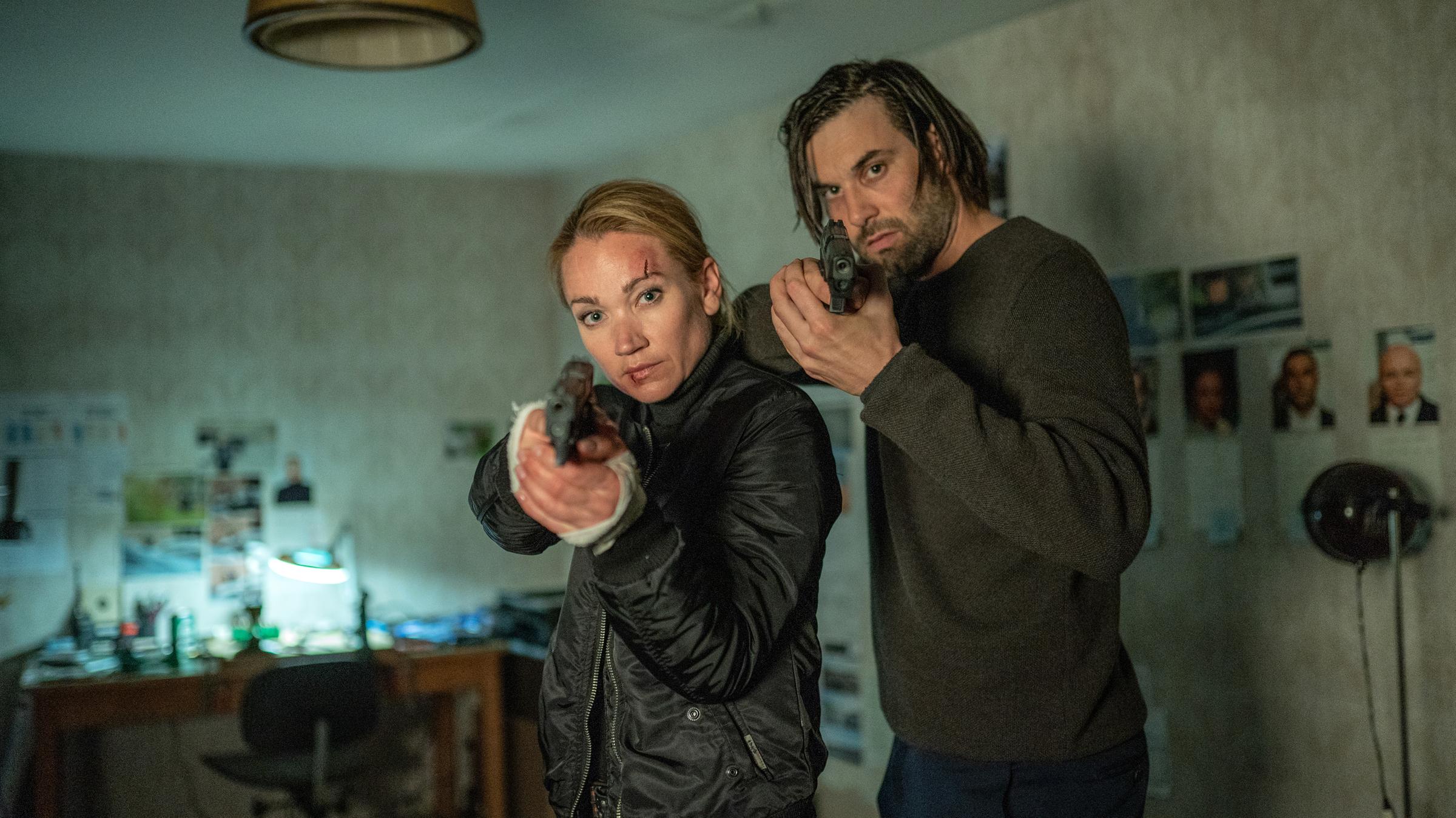 „Sarah Kohr – Schutzbefohlen“: Eine Frau und ein Mann stehen nebeneinander. Sie haben beide eine Waffe im Anschlag.