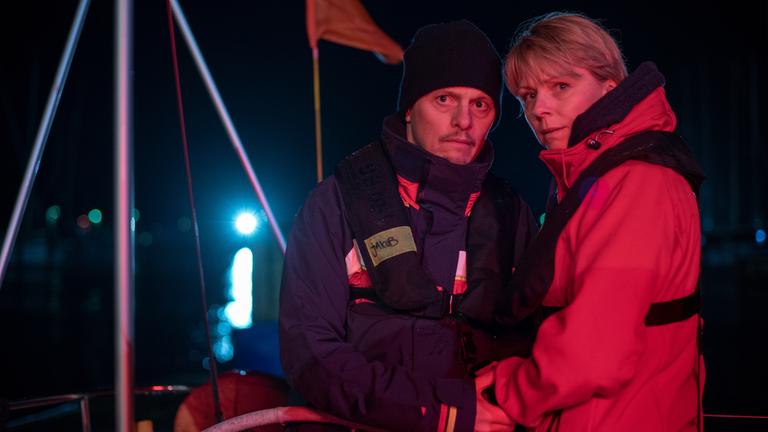 "Tod von Freunden - Sabine und Jakob": Jakob (Thure Lindhardt) und Charlie Jensen (Lene Maria Christensen) stehen kurz nach dem Unglück bei Nacht auf dem Segelschiff am Steuer, sie schauen ernst, er hält leicht ihre Hand.