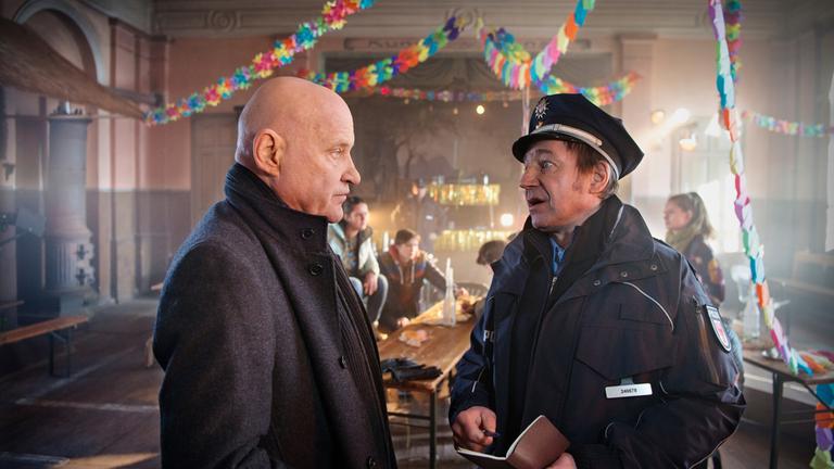 "Spreewaldkrimi - Totentanz": In einem mit Girlanden geschmückten Festsaal redet Fichte (Thorsten Merten) mit Thorsten Krüger (Christian Redl). Im Hintergrund sitzen Jugendliche an Biertischen.