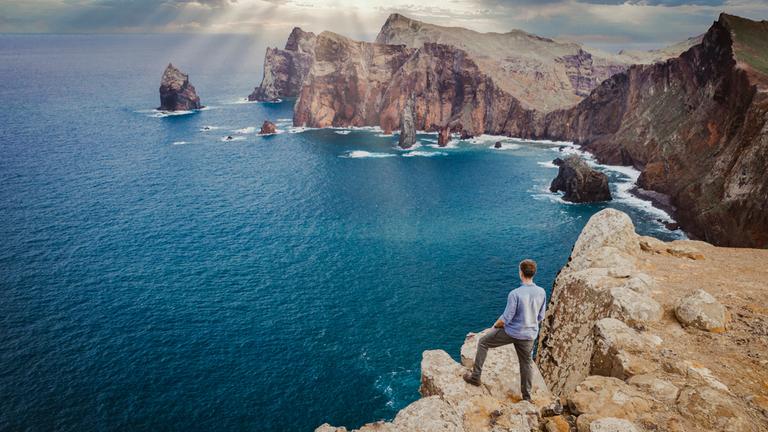 "Terra X - Faszination Erde - Mit Dirk Steffens - Makaronesien: Oasen in der blauen Wüste": Dirk Steffens steht auf einer Klippe mit Blick auf eine Felsenbucht.