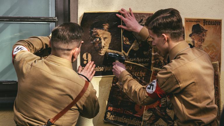 "Wie kam Hitler an die Macht - Der Teufelspakt": Nachgestellte Szene: SA-Männer in Uniform kleben Wahlplakat mit Adolf Hitler an die Wand.
